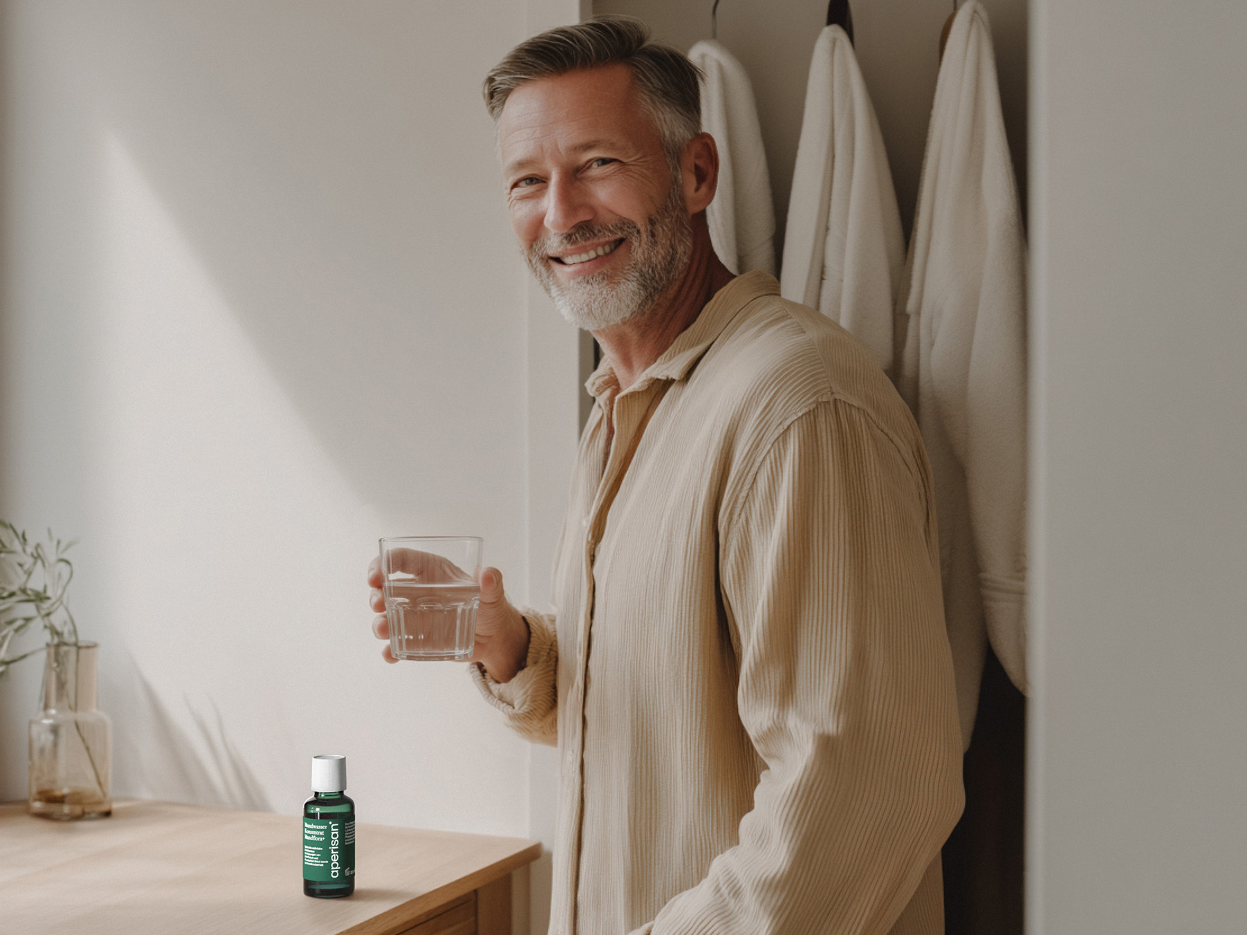 Mann genießt ein Glas Wasser mit Aperisan Mundwasser Konzentrat Mundflora+